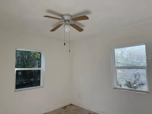 an empty room with a window and a fan