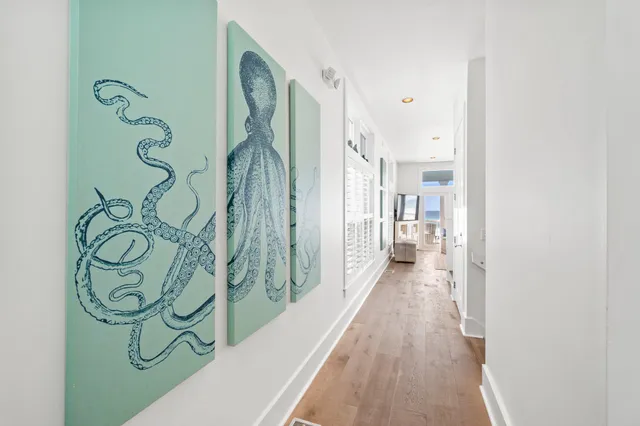 a view of a hallway with wooden floor and a bathroom