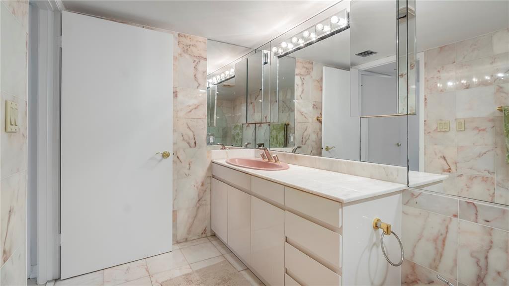 8877 Collins Avenue, Unit 1107 Surfside, FL 33154 - Photo 15 of 42 a bathroom with a sink vanity granite tub shower and a mirror