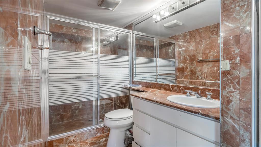 8877 Collins Avenue, Unit 1107 Surfside, FL 33154 - Photo 23 of 42 a bathroom with a sink a toilet a mirror and shower