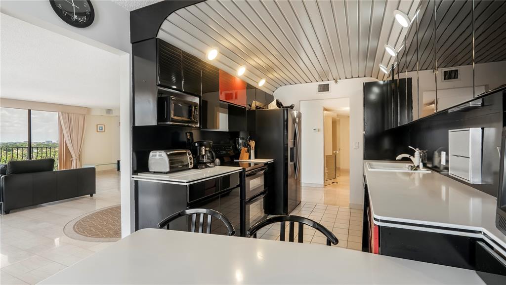 8877 Collins Avenue, Unit 1107 Surfside, FL 33154 - Photo 5 of 42 a kitchen with stainless steel appliances granite countertop a refrigerator a sink dishwasher a stove and white countertops with wooden floor
