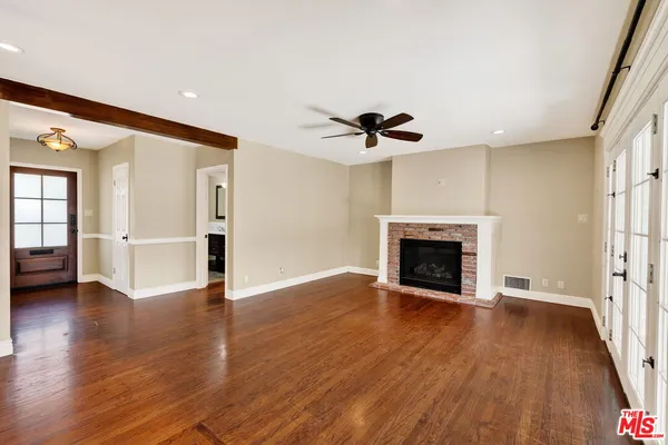 a view of an empty room with wooden floor fireplace and a window