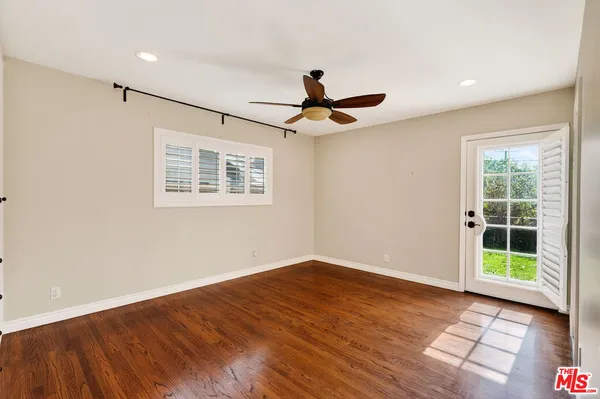 a view of empty room with wooden floor and fan