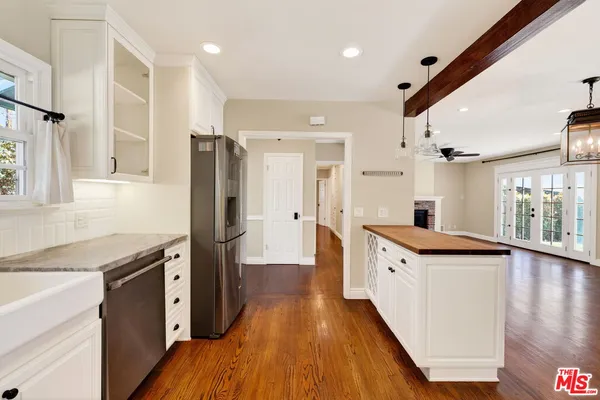 a kitchen with granite countertop a refrigerator a sink dishwasher and a stove with wooden floor