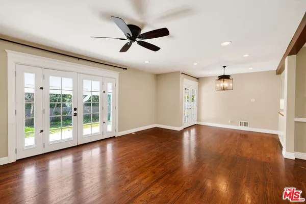 a view of empty room with wooden floor and fan