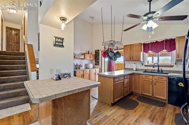 a kitchen with a stove a sink dishwasher and a refrigerator with wooden floor