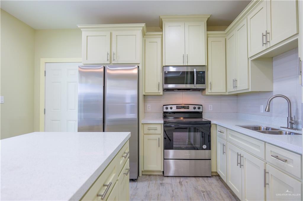 3086 Briggs Road, Unit D Weslaco, TX 78596 - Photo 4 of 10 a kitchen with kitchen island a sink stainless steel appliances and cabinets