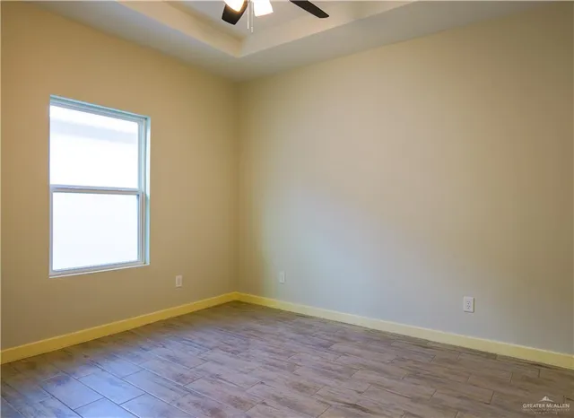 an empty room with a window and a ceiling fan