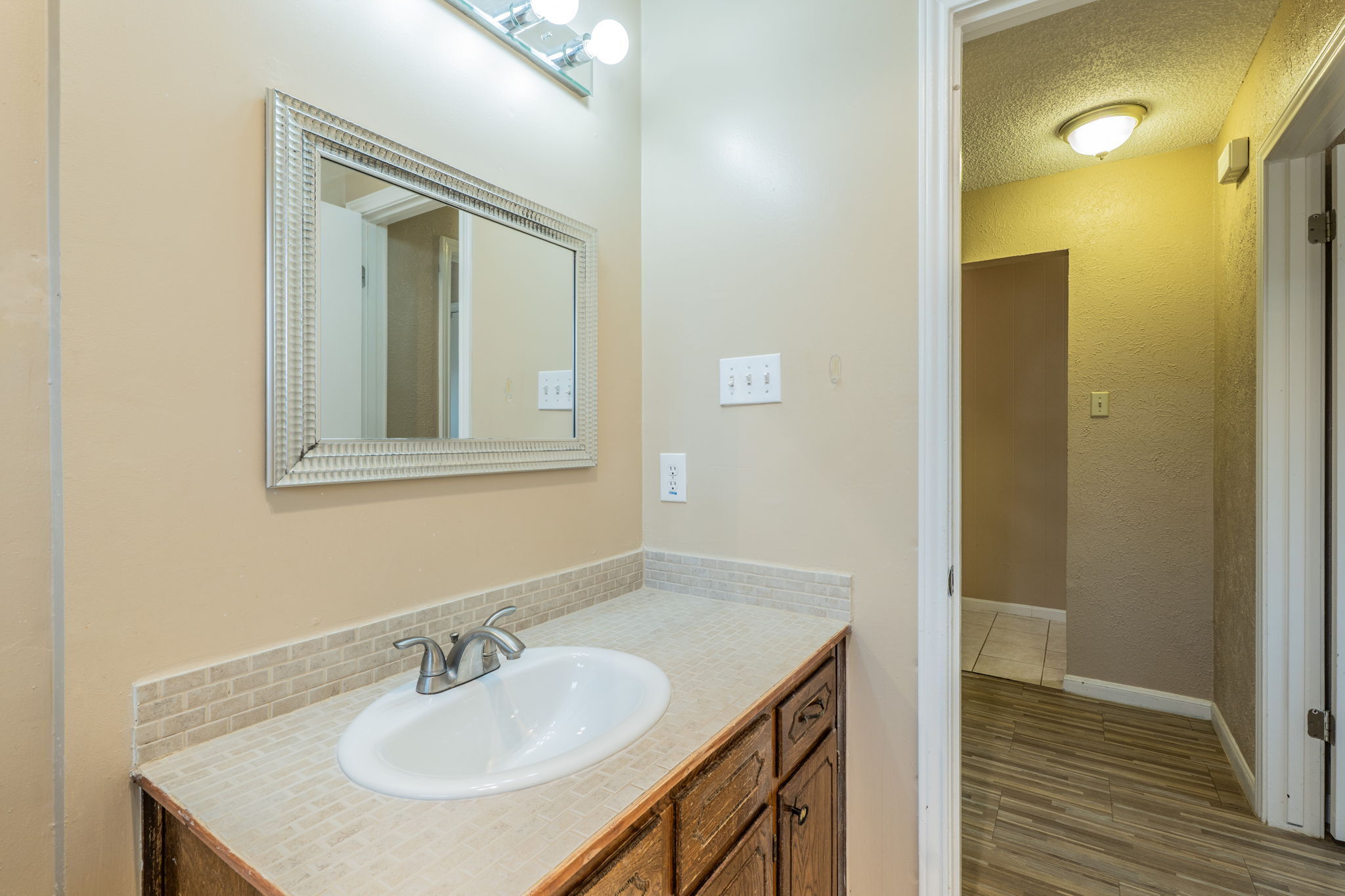 5628 Wagon Train Road Austin, TX 78749 - Photo 17 of 26 Functional vanity area links seamlessly to adjacent hallways featuring durable wood-look flooring.