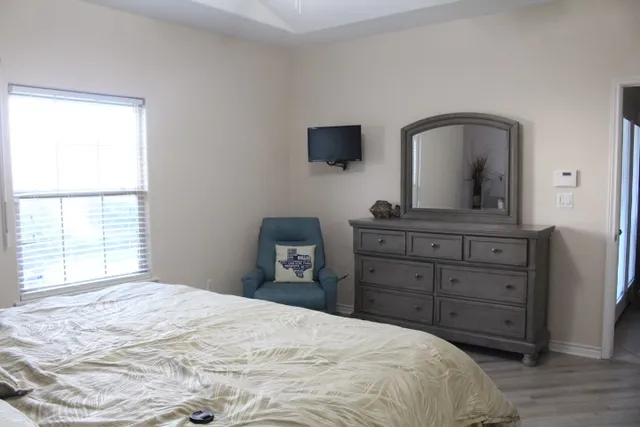 a bedroom with a bed and a flat tv screen on dresser