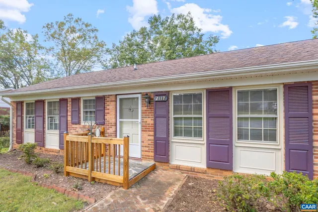 a view of a street with a yard and trees in the background