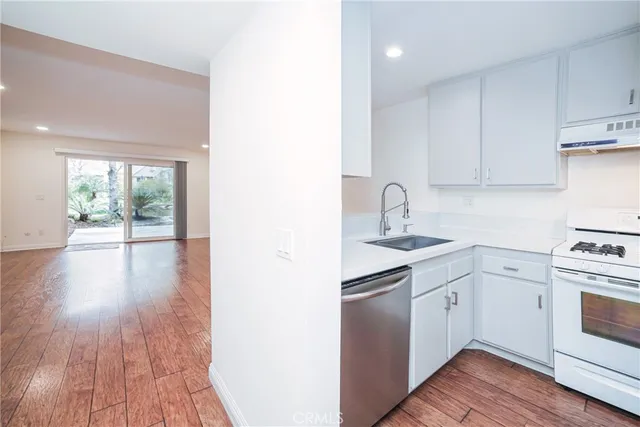 a kitchen with a sink cabinets stainless steel appliances and wooden floor