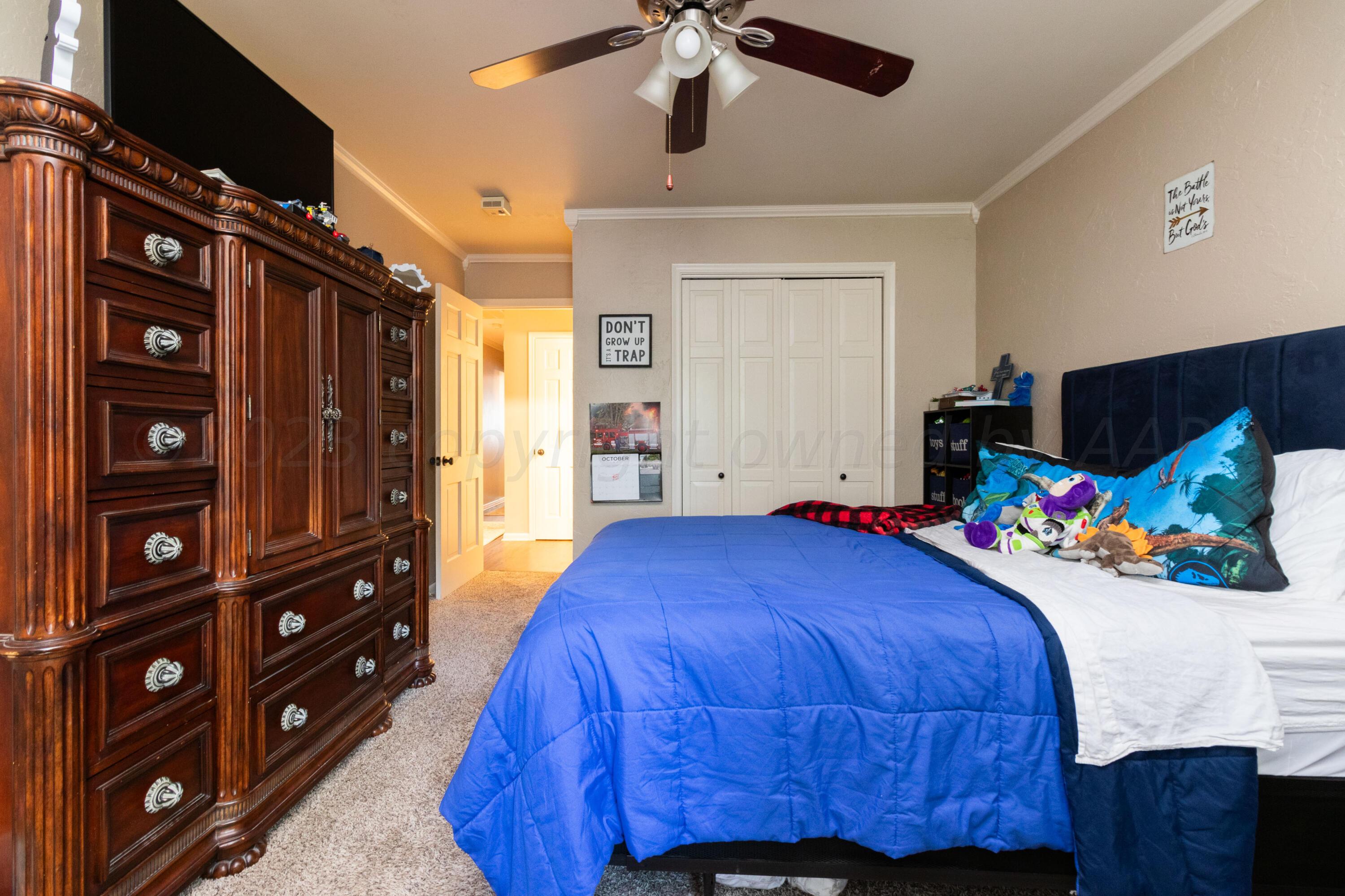 6704 Elmhurst Road Amarillo, TX 79106 - Photo 22 of 40 a bedroom with a bed a dresser and a chandelier