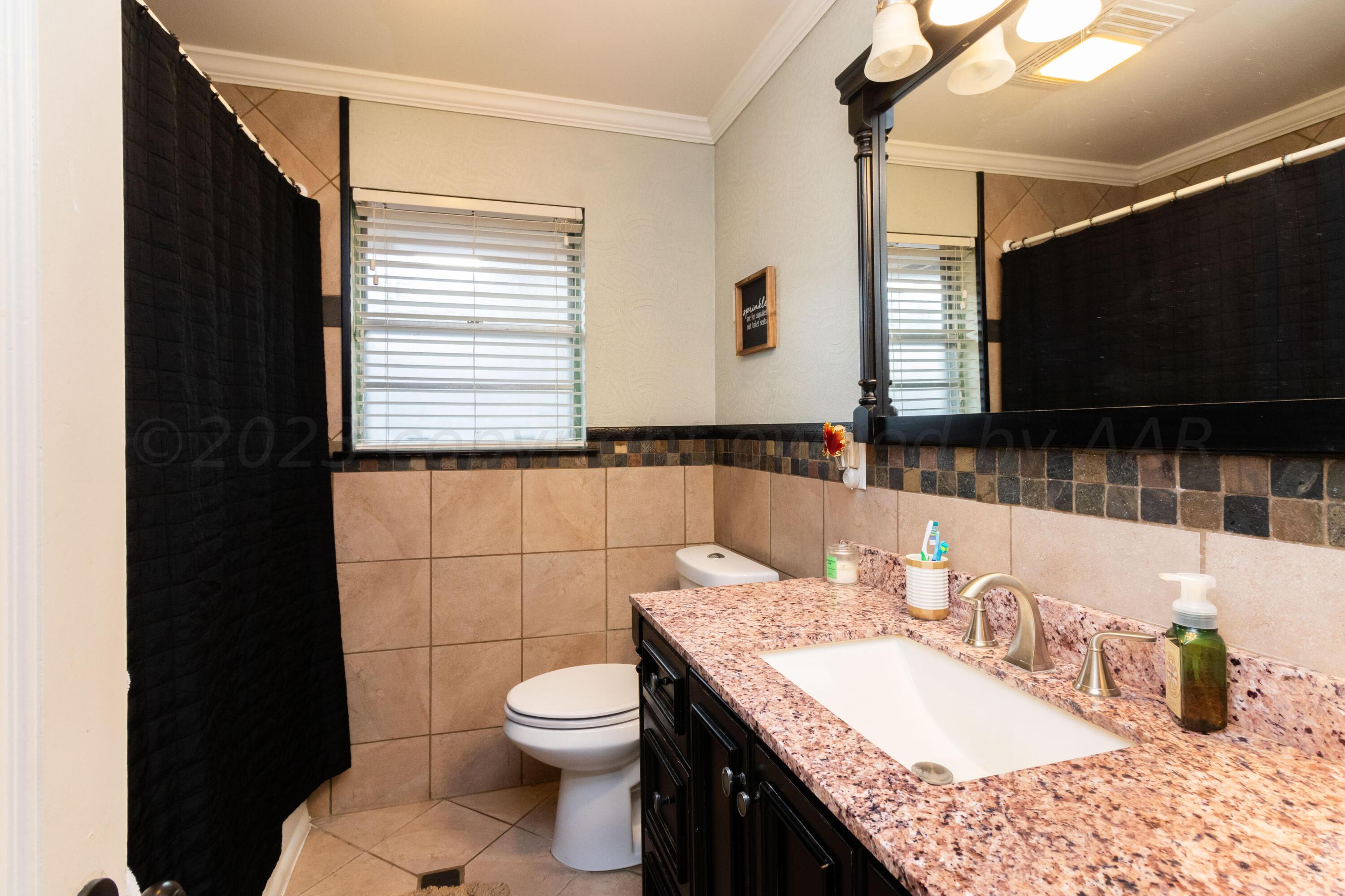 6704 Elmhurst Road Amarillo, TX 79106 - Photo 23 of 40 a bathroom with a granite countertop sink toilet and mirror