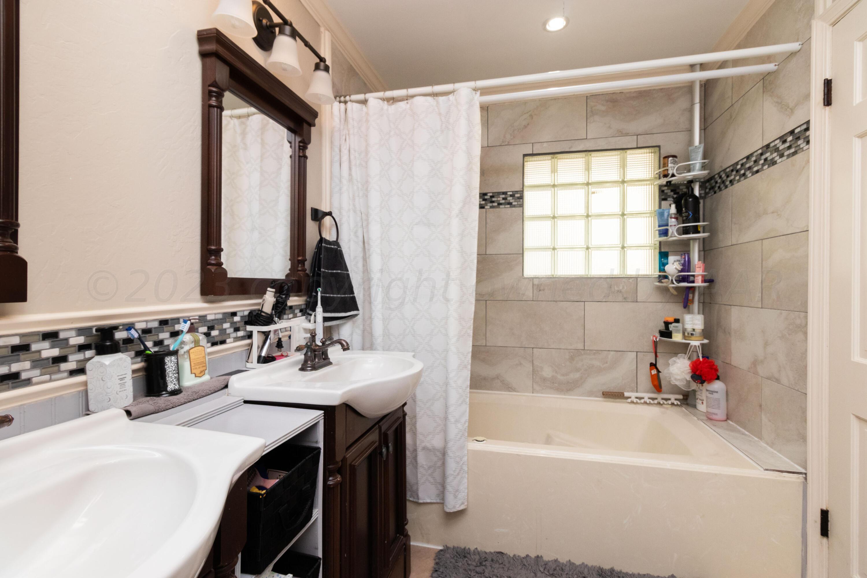 6704 Elmhurst Road Amarillo, TX 79106 - Photo 29 of 40 a bathroom with a tub sink vanity and a mirror