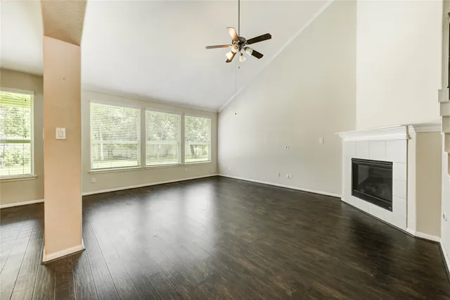 an empty room with wooden floor fireplace and windows