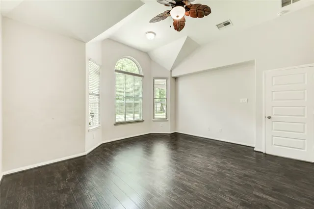 an empty room with wooden floor and windows