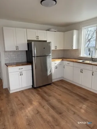 a kitchen with granite countertop a sink a stove a refrigerator and white cabinets