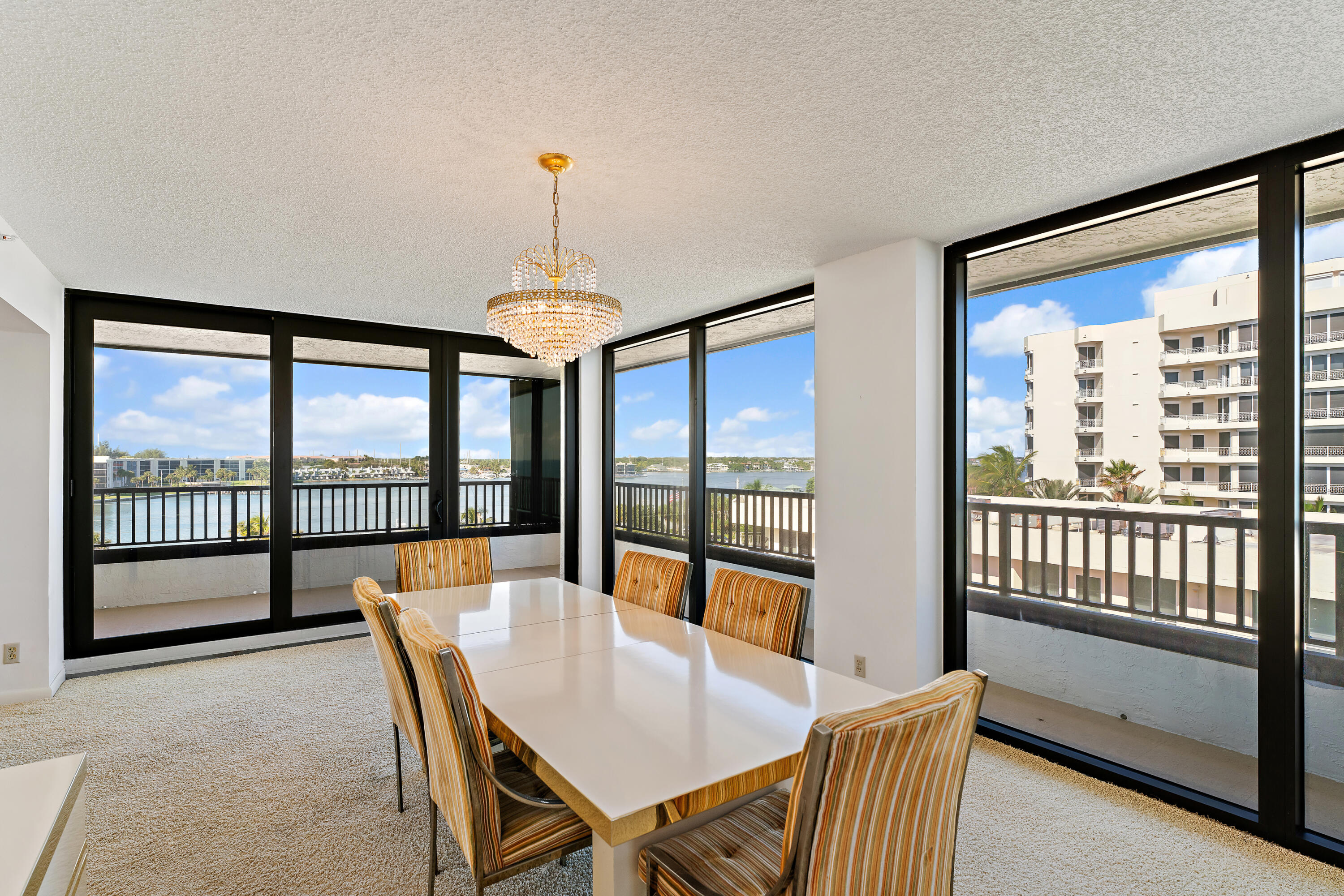 19900 South Beach Road, Unit 601 Jupiter, FL 33469 - Photo 23 of 84 a view of a dining room with furniture large windows and a chandelier
