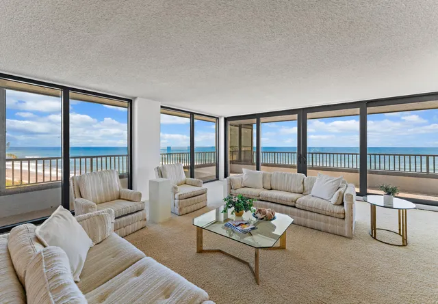 a living room with furniture and a large window with balcony view