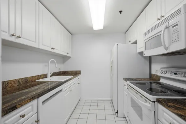a kitchen with granite countertop a sink stove and refrigerator
