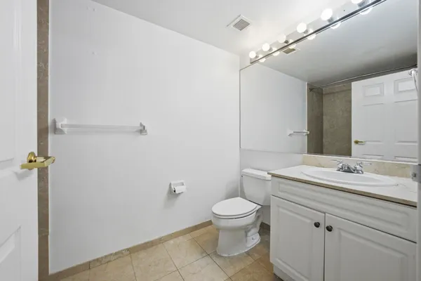 a bathroom with a granite countertop toilet sink mirror and vanity