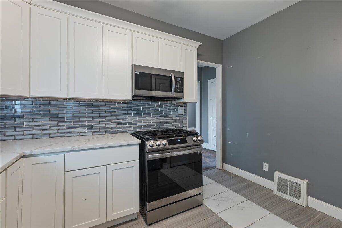 456 Bridge Street Gary, IN 46404 - Photo 19 of 27 a kitchen with granite countertop white cabinets and stainless steel appliances