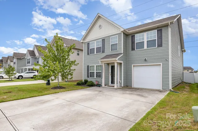 a front view of a house with a garden and trees