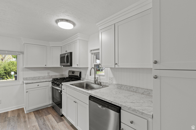 350 West 800 South, Unit 2 Logan, UT 84321 - Photo 4 of 22 Kitchen featuring stainless steel appliances, light countertops, white cabinetry, light wood finished floors, and a textured ceiling