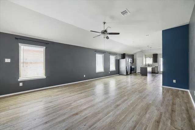 a view of an empty room with window and wooden floor