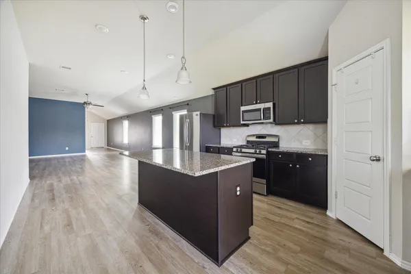 a kitchen with granite countertop a refrigerator and a stove top oven