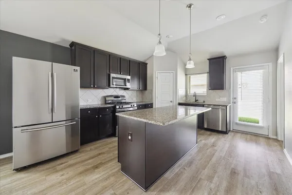 a kitchen with granite countertop a refrigerator oven a sink dishwasher and a stove with wooden floor