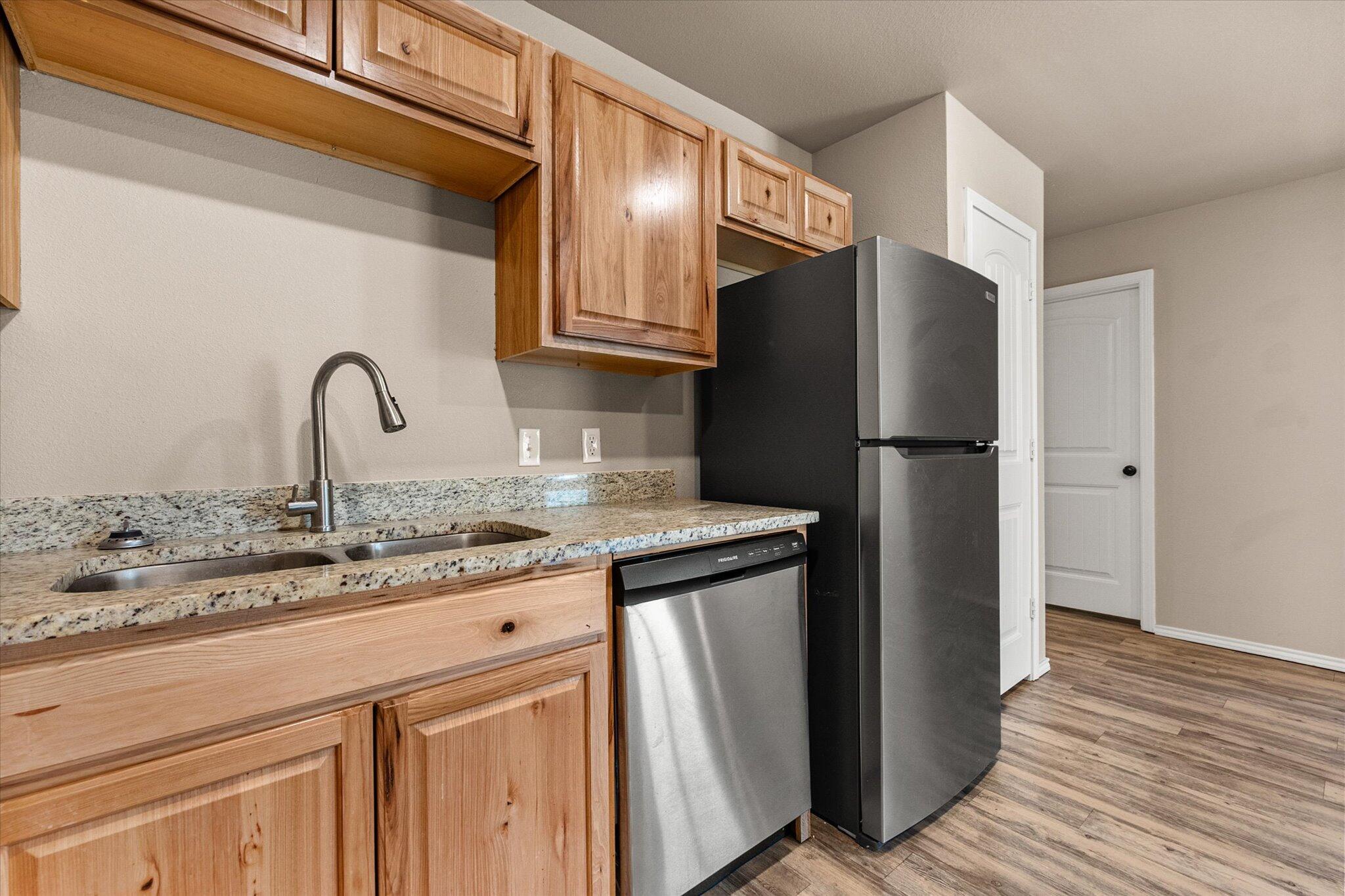 7412 5th Street, Unit 1 Lubbock, TX 79416 - Photo 9 of 16 a kitchen with granite countertop a refrigerator and a sink