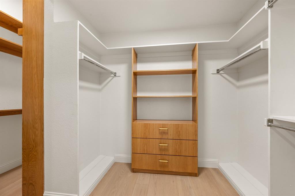 6403 Genstar Lane Dallas, TX 75252 - Photo 21 of 34 Custom closet system featuring wood-finish shelving, built-in drawers with gold-tone hardware, and hanging rods