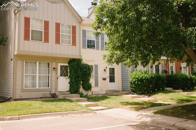 a view of a house with a yard and large tree