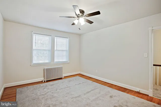 an empty room with chandelier fan and windows
