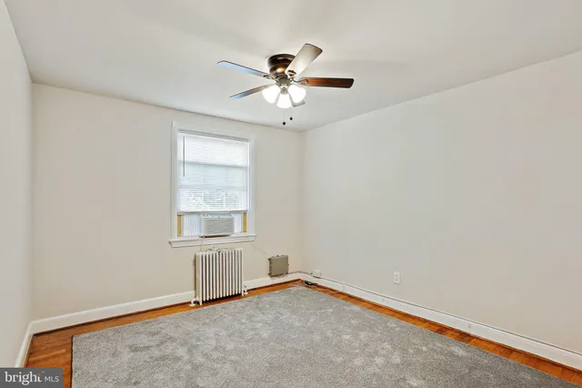 an empty room with a window and a ceiling fan