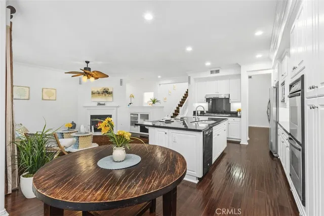 a kitchen with stainless steel appliances granite countertop a sink a stove a dining table and chairs