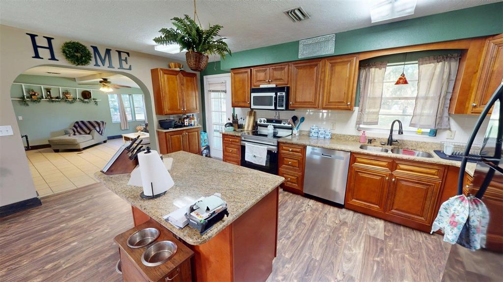 635 Bost Road Wauchula, FL 33873 - Photo 18 of 39 a kitchen with stainless steel appliances granite countertop a refrigerator a sink dishwasher a stove and a dining table with wooden floor
