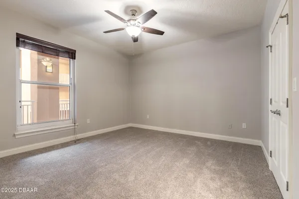 an empty room with chandelier fan and windows