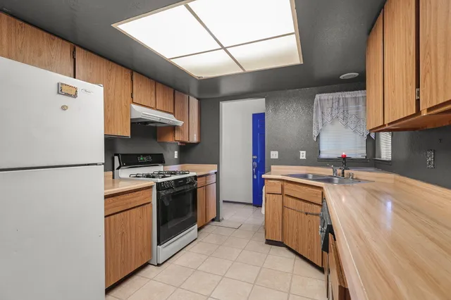 a kitchen with granite countertop a sink stove and refrigerator