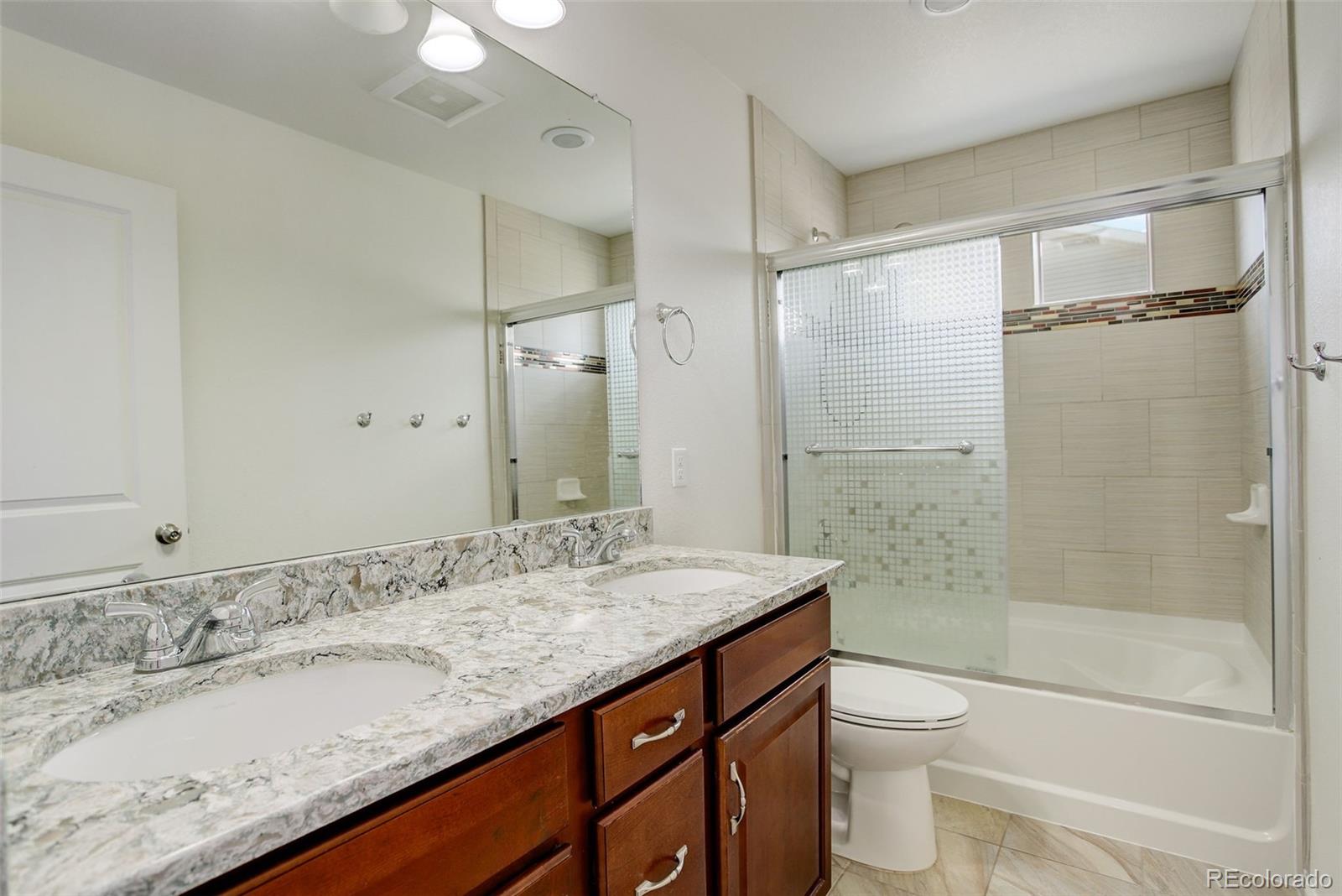 4971 Ceylon Way Denver, CO 80249 - Photo 22 of 40 a bathroom with a granite countertop sink toilet and shower