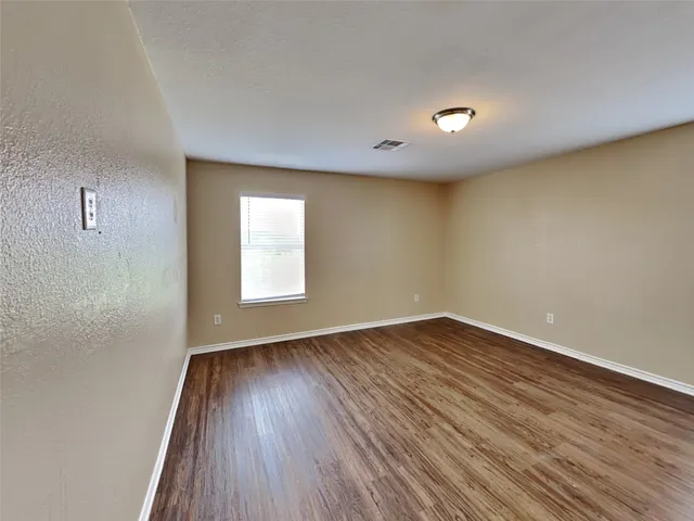 a view of an empty room with wooden floor and closet