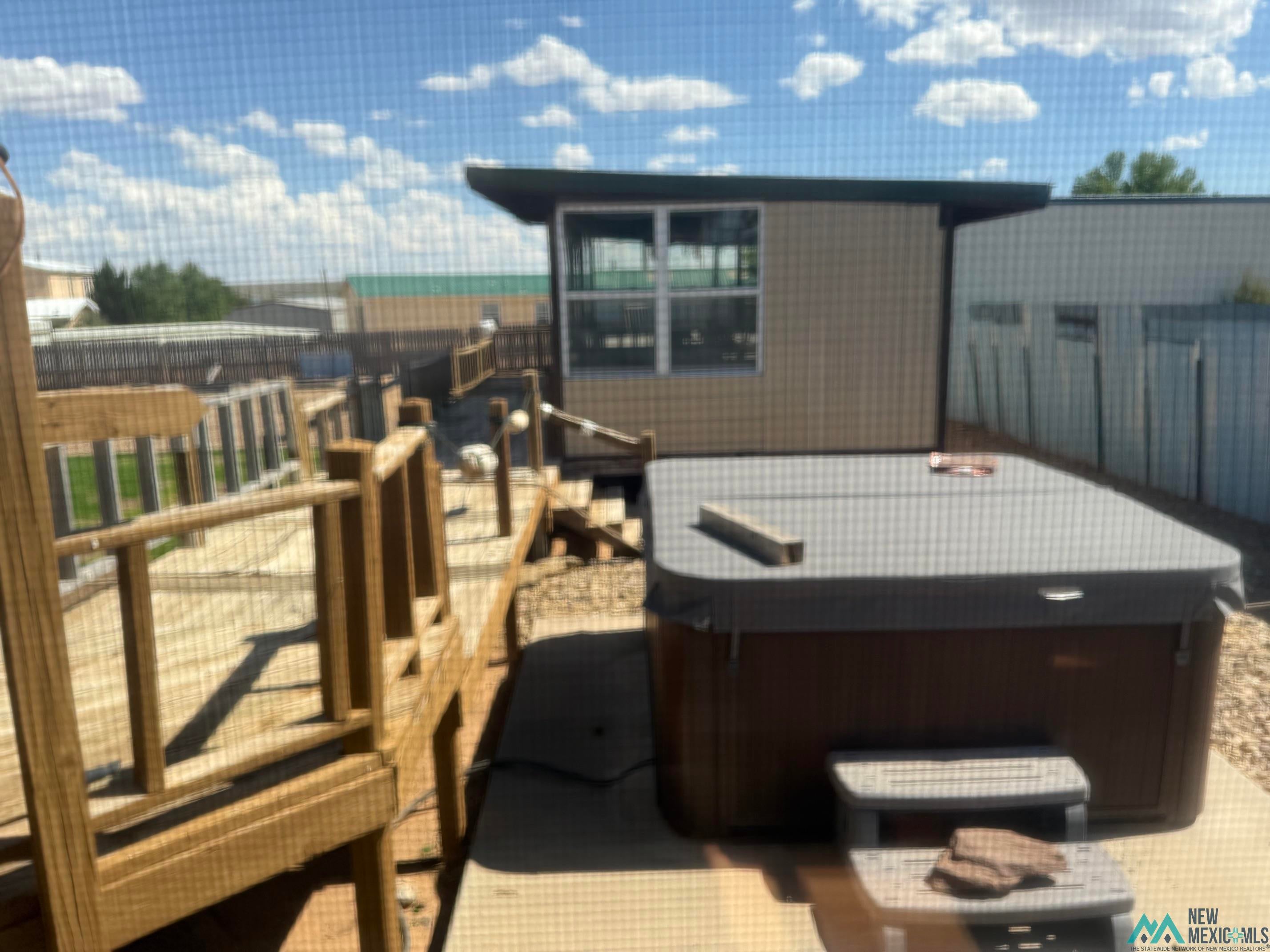 104 Shawnee Road Logan, NM 88426 - Photo 8 of 36 Outdoor spa situated on a concrete pad, complemented by a multi-level wood deck with railings and integrated lighting