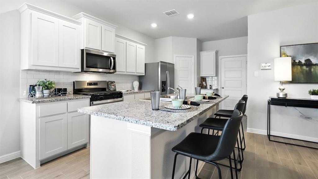 113 Tyler Street Grandview, TX 76050 - Photo 4 of 40 a kitchen with stainless steel appliances granite countertop a sink a stove a microwave a refrigerator and cabinets
