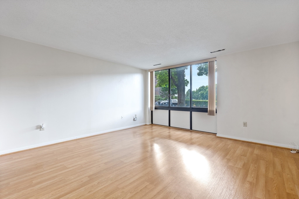 1006 Paradise Road, Unit 1A Swampscott, MA 01907 - Photo 3 of 18 a view of an empty room with wooden floor and a window