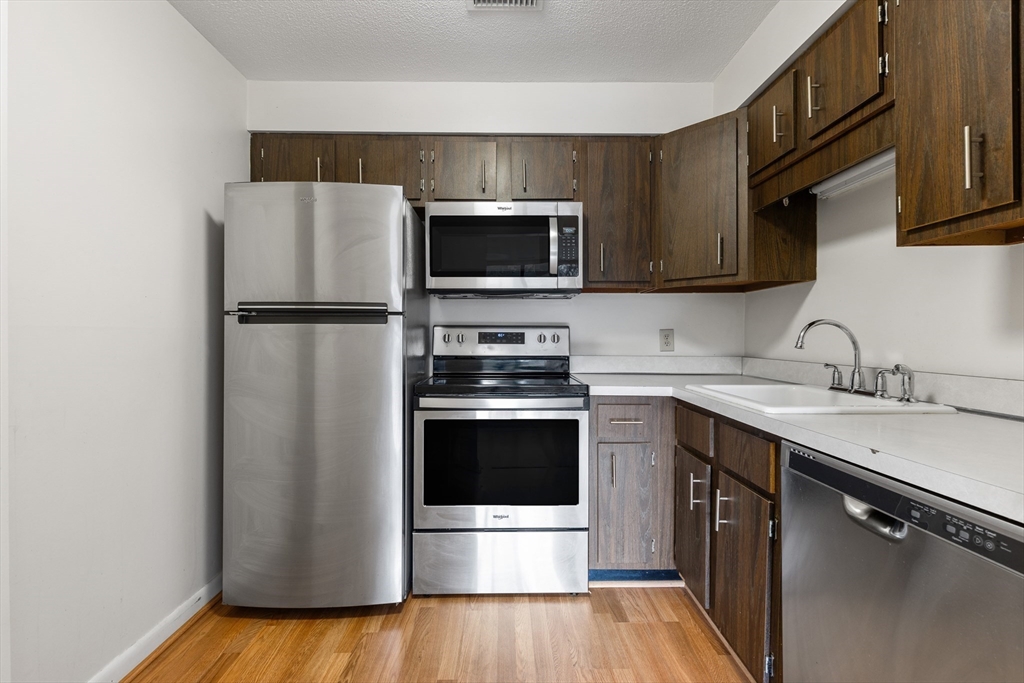 1006 Paradise Road, Unit 1A Swampscott, MA 01907 - Photo 4 of 18 a kitchen with a sink a microwave a refrigerator and cabinets