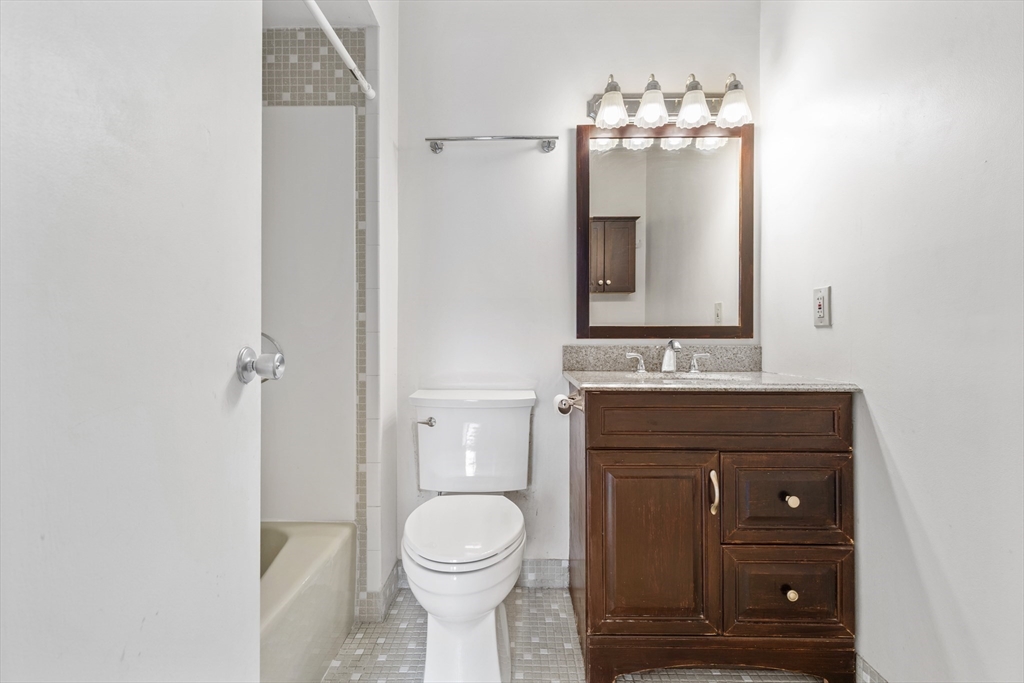 1006 Paradise Road, Unit 1A Swampscott, MA 01907 - Photo 9 of 18 a bathroom with a toilet a sink a vanity and mirror