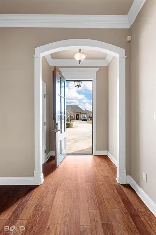 an empty room with wooden floor and kitchen view