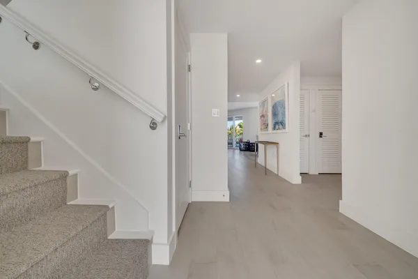 a view of a hallway with wooden floor and a bathroom